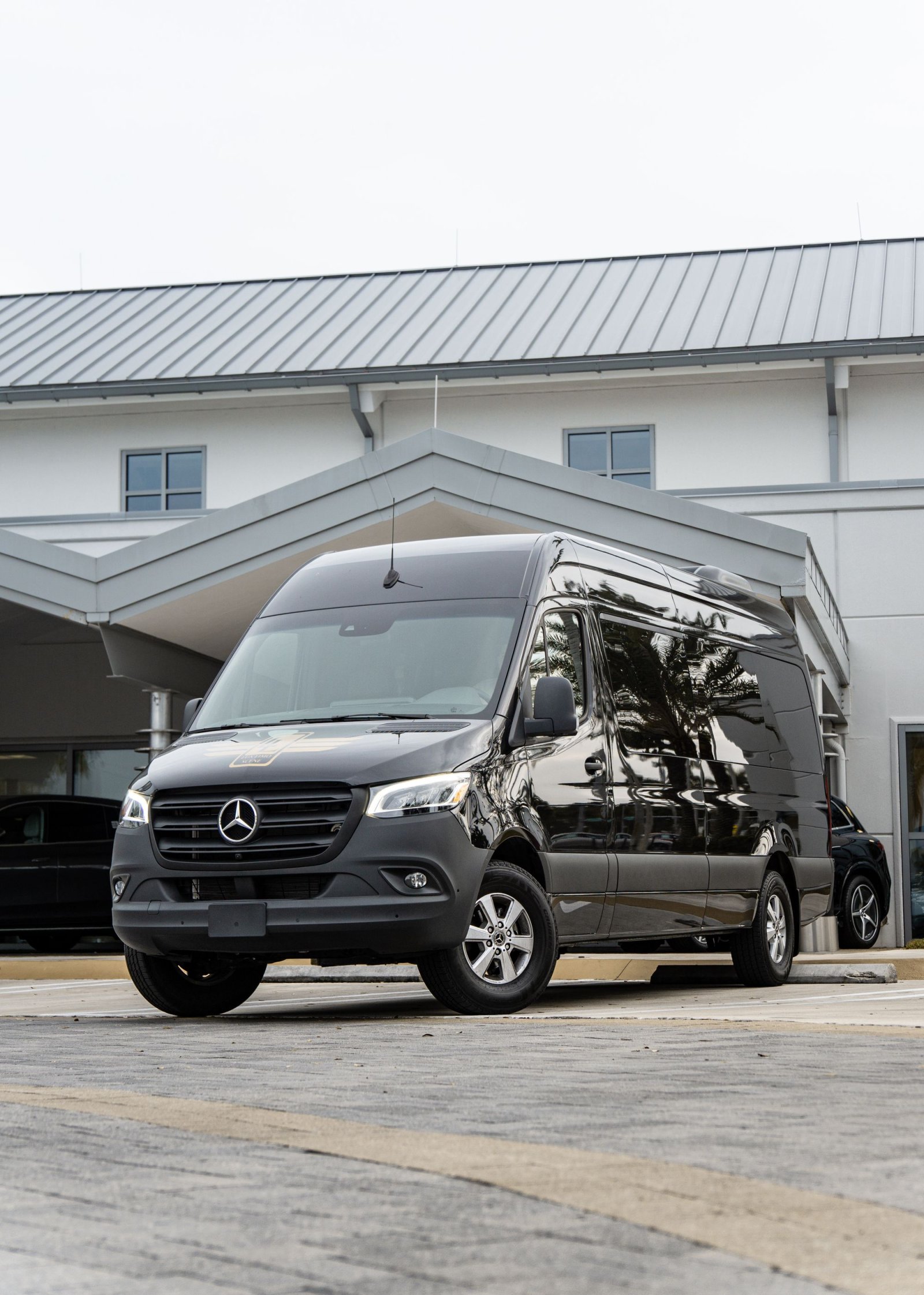 Black Mercedes-Benz Sprinter executive van outside a modern building