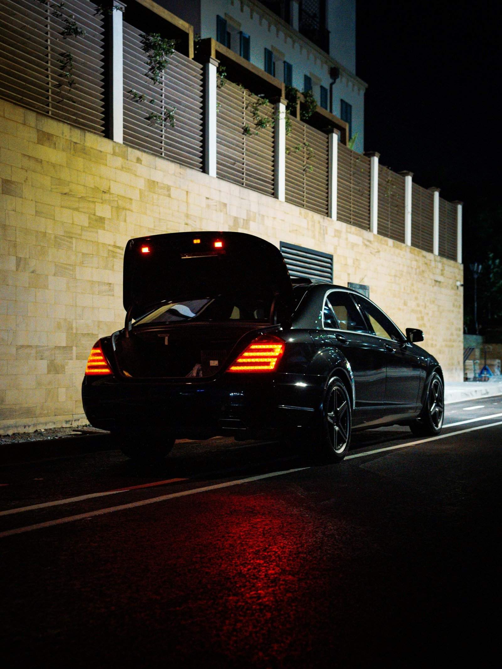 Black luxury car with the trunk open for luggage at night