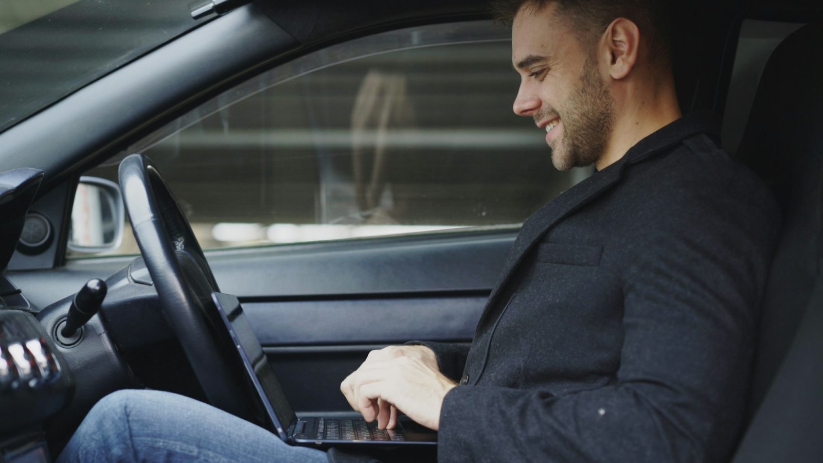 Business traveller working on a laptop inside a car